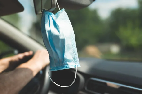 Medical protective mask hanging on the mirror in the car.