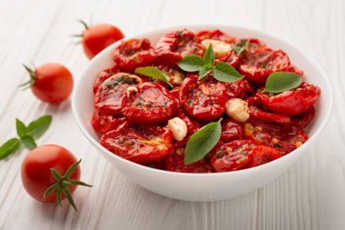 Bir kase güneşte kurutulmuş domates zeytinyağıyla ahşap arka planda.