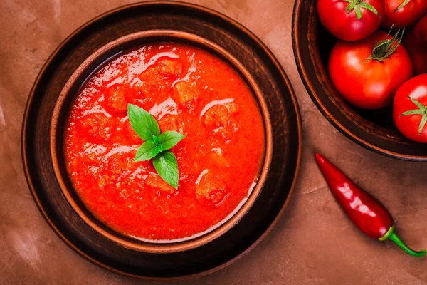 ガスパチョのスープと新鮮なトマトのボウルのトップビュー茶色の背景に近い — ストック写真