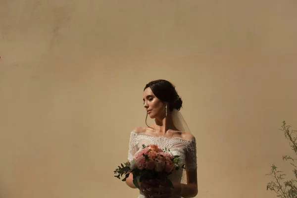 Retrato de la novia con un ramo de flores en el fondo de la pared — Foto de Stock