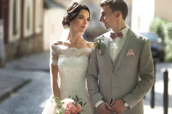 Een verliefde paar voor pasgetrouwden wandelingen in de stad, en glimlach. De bruid in een mooie jurk, de bruidegom stijlvol gekleed — Stockfoto