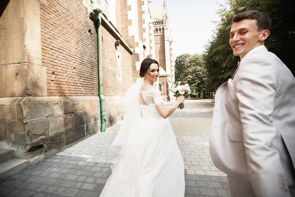 Schönes frisch vermähltes Paar spaziert in der Nähe der alten christlichen Kirche — Stockfoto