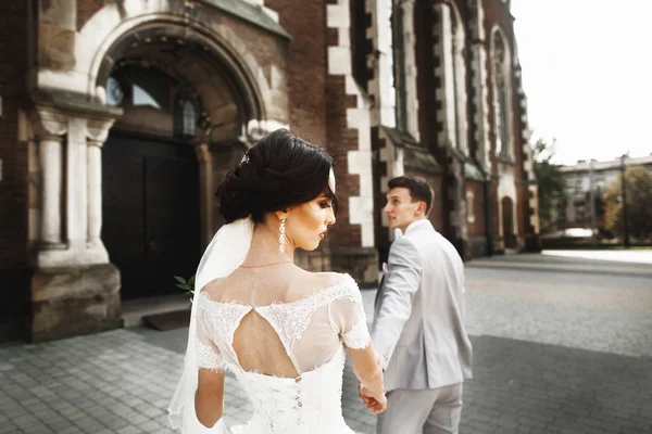 Pasangan pengantin baru yang cantik berjalan di dekat gereja tua Kristen — Stok Foto