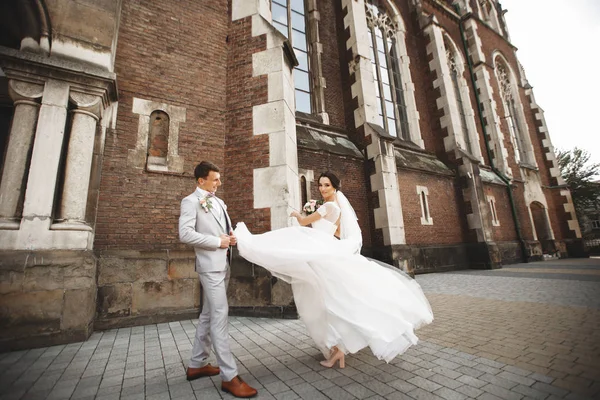 Menakjubkan tersenyum pasangan pernikahan. Cantik pengantin dan bergaya pengantin pria dekat gereja — Stok Foto