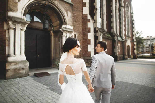 Pasangan pengantin baru yang cantik berjalan di dekat gereja tua Kristen — Stok Foto