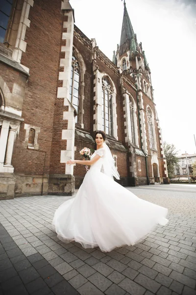 Die Braut auf einem Spaziergang nahe der Mauer der alten gotischen Kirche — Stockfoto