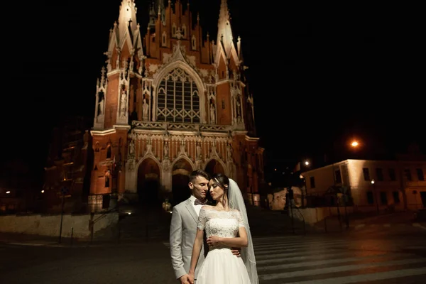 Nacht fotosessie van bruidspaar in Krakau. Jonggehuwden wandeling rond de kerk — Stockfoto