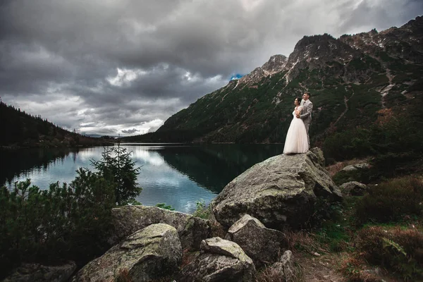 Un jeune couple de mariés bénéficie d'une vue sur la montagne au bord d'un lac Morskie Oko . — Photo