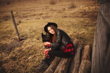 mutlu genç kadın fron eski ahşap evin onun siyah köpek ile oturuyordu