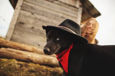 Eski ahşap ev fron onun siyah köpeği ile plaing mutlu genç kadın. Kız köpeği için bir şapka çalışır