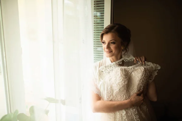 Hermoso estilo de novia. Boda chica de pie en vestido de novia de lujo cerca de la ventana — Foto de Stock