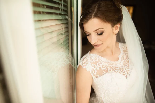 美丽的新娘风格。婚礼女孩站在豪华婚纱附近的窗口 — 图库照片