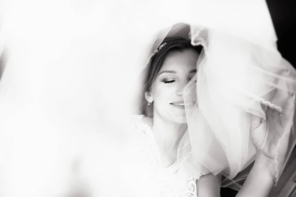 Piękny styl panny młodej. Ślub dziewczyna stoją w luksusowej sukni ślubnej w pobliżu okna. Czarno-białe — Zdjęcie stockowe