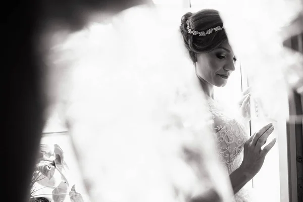 美丽的新娘风格。婚礼女孩站在豪华婚纱附近的窗口。黑色和白色 — 图库照片