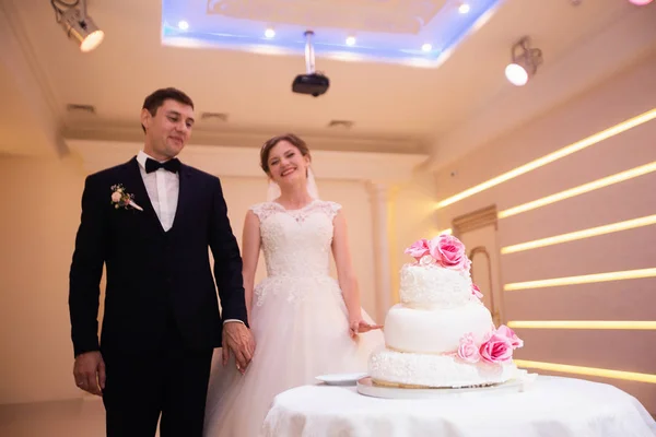 Счастливая молодая супружеская пара режет торт в ресторане — стоковое фото