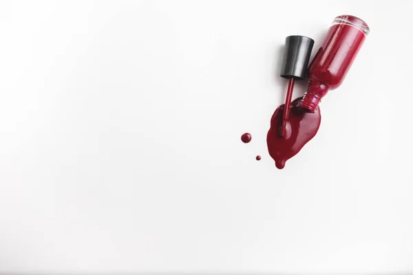 Fechar acima de uma garrafa vermelha do esmalte da unha e gota no fundo branco — Fotografia de Stock