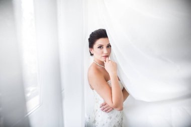 Perde altında poz beyaz elbiseli güzel seksi gelin