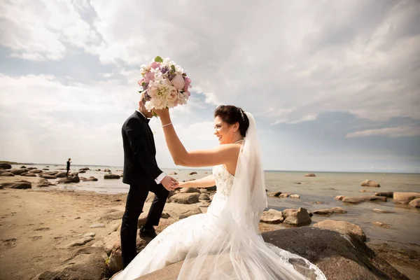 海岸に立っているスタイリッシュな結婚式のカップル。新婚夫婦は海のそばを歩いている — ストック写真
