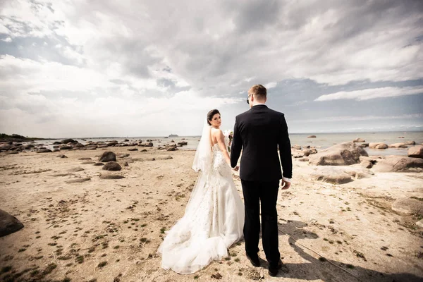 Стильная свадебная пара, стоящая на берегу моря. Молодые люди идут по морю — стоковое фото