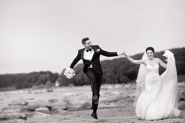 Feliz joven pareja de boda divirtiéndose en la playa. Blanco y negro —  Fotos de Stock