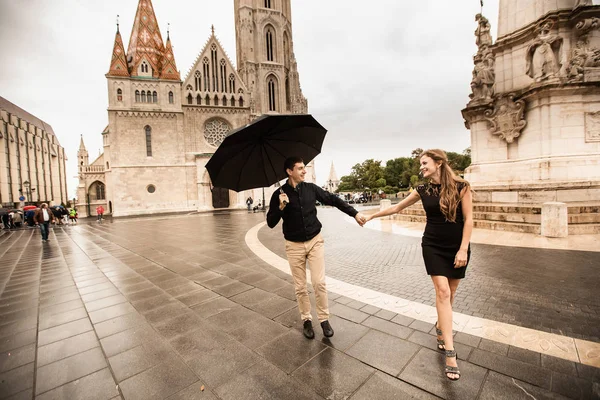 Jovem casal com guarda-chuva andando em Budapeste em um dia chuvoso. História de amor — Fotografia de Stock