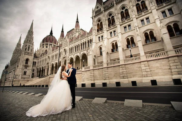 Gelin ve damat eski kasaba sokakta sarılmak. Düğün çift Budapeşte 'de Parlamento Evi yakınında yürüyor.