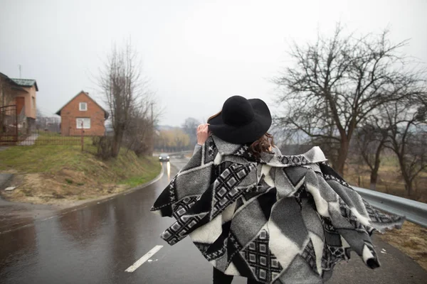 비오는 날 도로를 따라 걷는 검은 모자를 쓴 소녀 — 스톡 사진