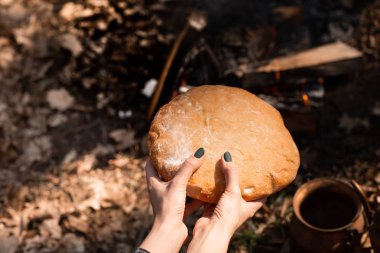 Bir kadın elinde taze paspası ekmek closeup. Ormanın arka planı