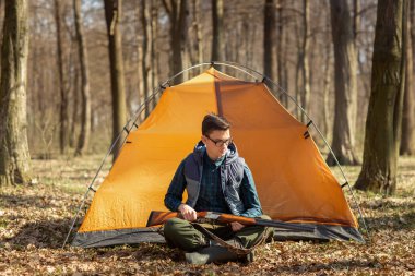 Çadırın yanında oturan ormanda silahlı avcı