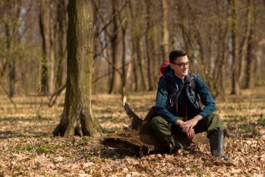 Sırt çantalı genç adam ormanda yürüyüş yapıyor. Doğa ve fiziksel egzersiz kavramı