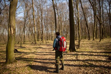 Sırt çantalı genç adam ormanda yürüyüş yapıyor. Doğa ve fiziksel egzersiz kavramı