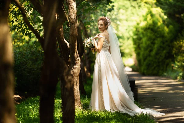 Novia en vestido de novia de moda sobre fondo natural. Un hermoso retrato de mujer en el parque. Vista trasera — Foto de Stock