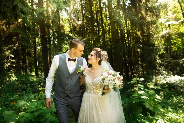 Egy esküvő pár élvezi séta az erdőben. Newlyweds ölelés és tartsa kezét — Stock Fotó
