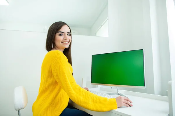 Retrato de una hermosa mujer sonriente, trabajando en el ordenador con pantalla verde, en un ambiente de oficina —  Fotos de Stock