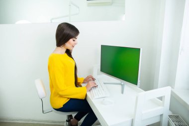 Bir ofis ortamında, yeşil ekran ile bilgisayarda çalışan güzel bir gülümseyen kadın portresi