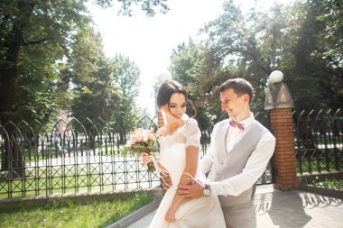 Gelin ve damat düğün günü güzel bir parkta yürüyüş, birbirlerinin zevk sonunda gülümseyen