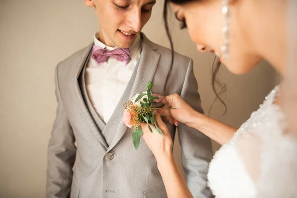 Традиционно невеста в доме прикасается к небольшому букету для жениха. Букет жениха рядом с рукой на костюме — стоковое фото