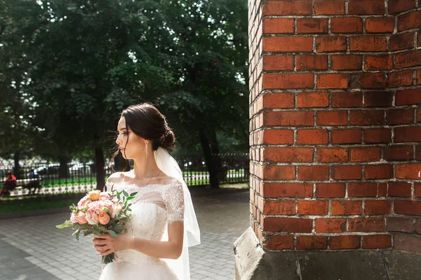 Gyönyörű menyasszony pózol, közel a vörös falon a régi gótikus templom — Stock Fotó