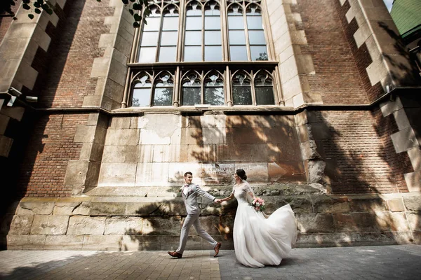 Schönes frisch vermähltes Paar spaziert in der Nähe der alten christlichen Kirche — Stockfoto