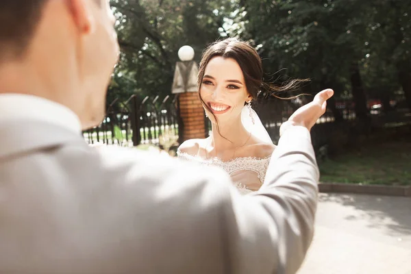 Hermosa joven novia en vestido blanco con estilo, sonriendo se encuentra con su novio en el parque —  Fotos de Stock