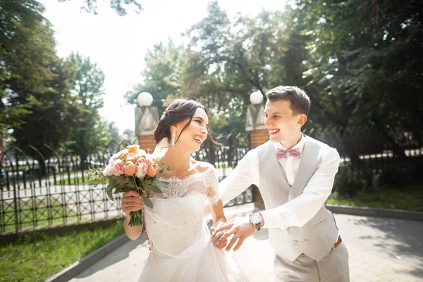 Novia y novio en el día de la boda caminando en un hermoso parque, final sonriente disfrutando el uno del otro —  Fotos de Stock