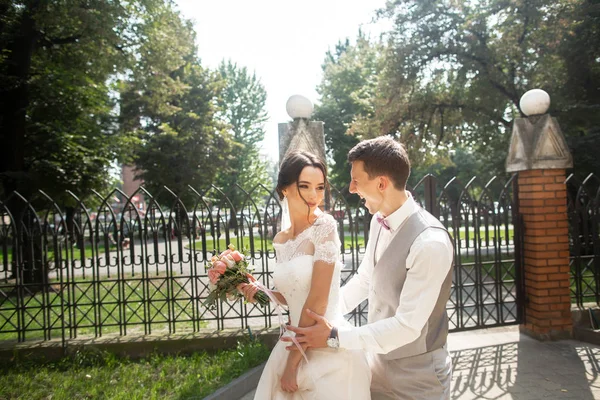 Novia y novio en el día de la boda caminando en un hermoso parque, final sonriente disfrutando el uno del otro —  Fotos de Stock