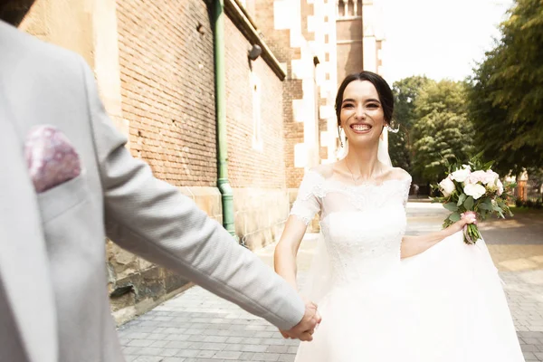 Pasangan pengantin baru yang cantik berjalan di dekat gereja tua Kristen — Stok Foto