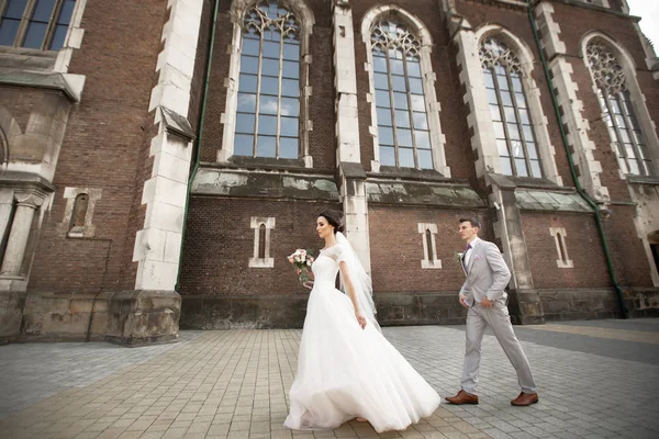 Mooie jonggehuwde paar lopen in de buurt van de oude christelijke kerk — Stockfoto