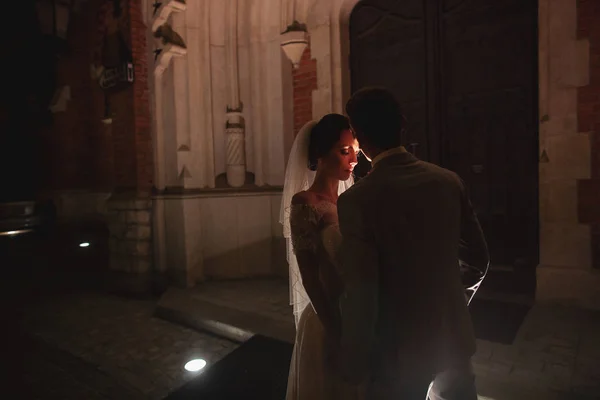 Night photosession of wedding couple in Krakow. Newlyweds walk around the church