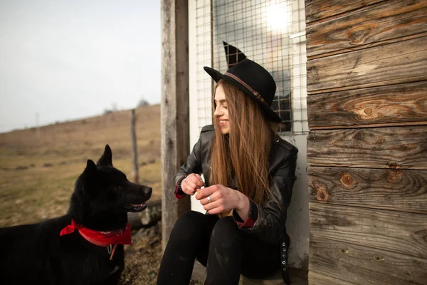 Eski ahşap evin fron onun siyah köpek Brovko Vivchar ile plaing mutlu genç kadın