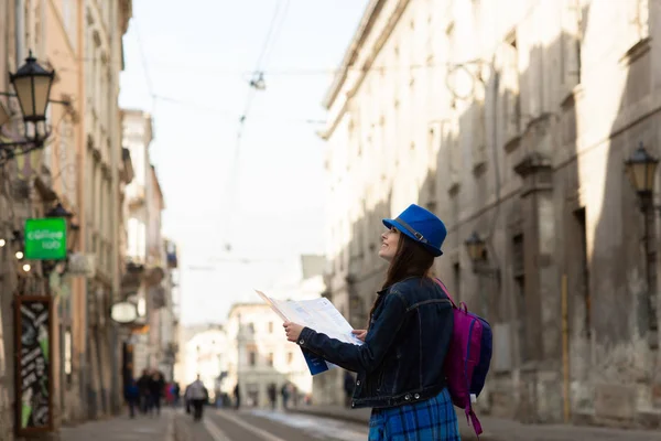 Giovane donna elegante a piedi sulla strada della città vecchia, viaggiare con zaino e cappello blu. Ucraina, Leopoli — Foto Stock