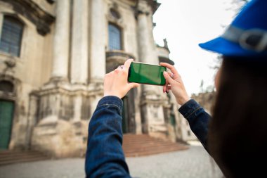 Gülümseyen genç kız eski şehir Lviv mimari anıtların fotoğraflarını çekiyor. Ukrayna