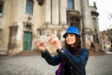 Gülümseyen genç kız eski şehir Lviv mimari anıtların fotoğraflarını çekiyor. Ukrayna