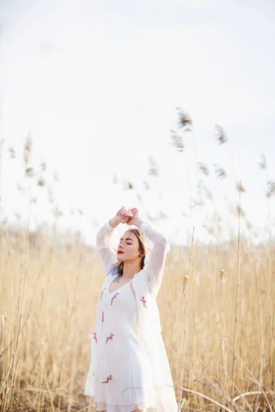 Portret młodej pięknej dziewczyny w białej sukni w polu pszenicy, chodzenie, beztroki. Cieszący się pięknym, słonecznym dniem — Zdjęcie stockowe